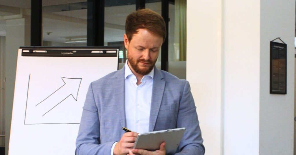Marketingberater für KMU vor Flipchart, der stehend an seinem Tablet arbeitet